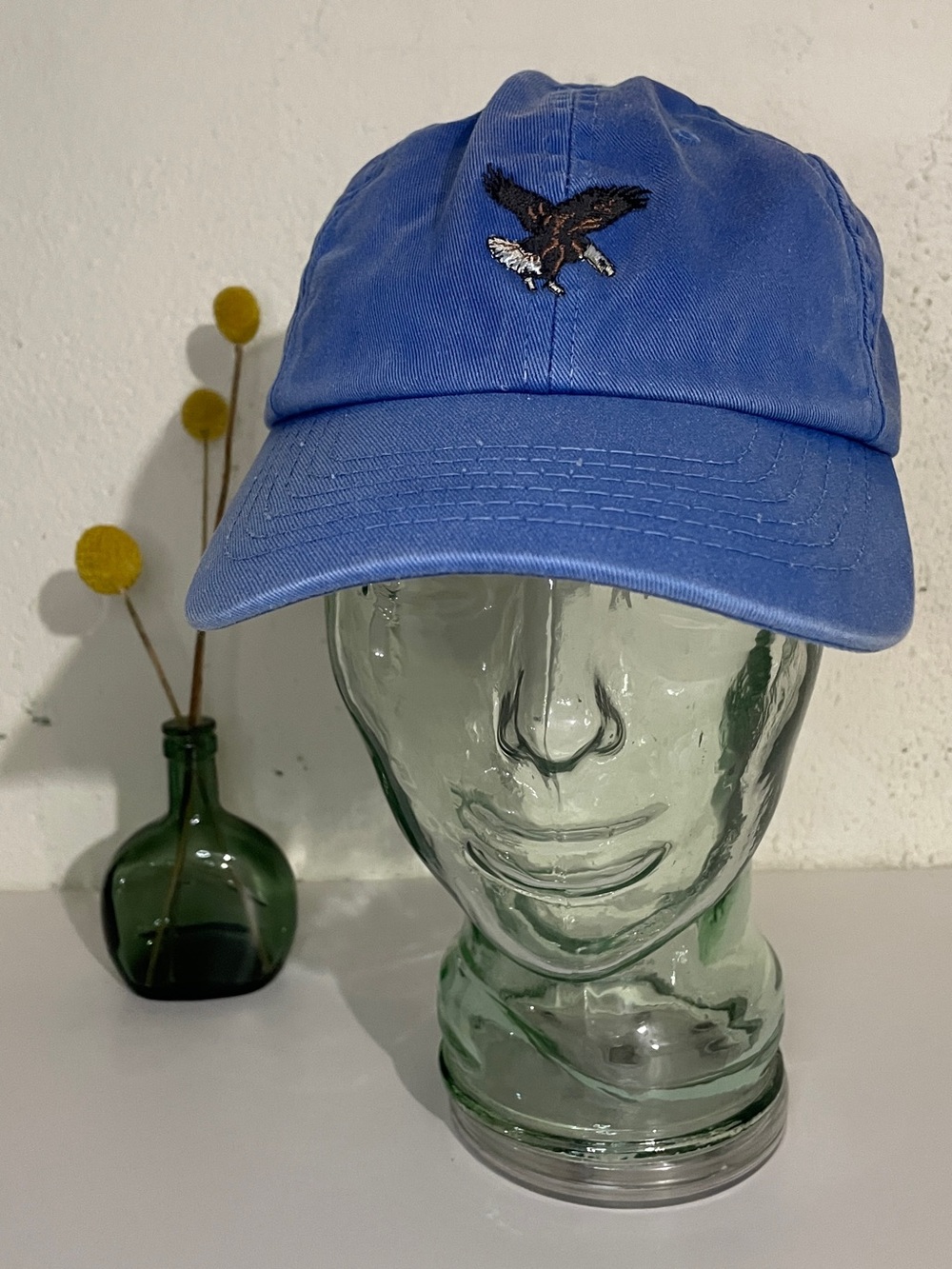 Filson blue baseball hat with brown leather adjustable strap, bald eagle